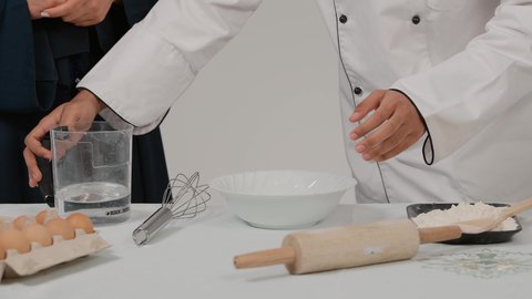Preparing delicious baked goods and pastries, enjoying teamwork in the cooking profession, participating in preparing delicious recipes, a close-up of the hands of an Emirati Gulf Arab man and woman participating in preparing food, a Gulf man pouring water into a bowl to prepare food