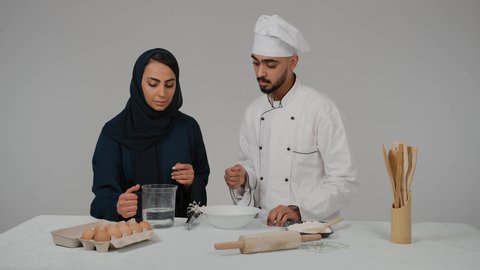الاستمتاع بالعمل الجماعي في مهنة الطبخ، إعداد المخبوزات والمعجنات الشهية، المشاركة في تحضير الوصفات الشهية، تصوير مقرب لرجل وامرأة عربيين خليجيين اماراتيان يتشاركان في تجهيز الطعام، امراة خليجيه تقوم بسكب المياه في الوعاء لاعداد الطعام