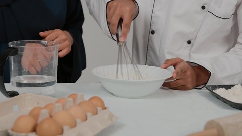 تحضير المكونات لصناعة الخبز، تصوير مقرب لرجل وامرأة عربيين خليجيين اماراتيان يتشاركان في تجهيز الطعام، المشاركة في تحضير الوصفات الشهية، تصوير مقرب ليد شيف خليجي يرتدي الزي الخاص بمزاولة المهنة يحمل بيده الشوبك (النشابة) يقوم بتحضير الطعام، أدوات خاصة بالمطبخ