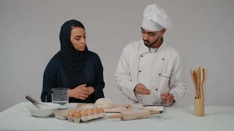 الاستمتاع بالعمل الجماعي في مهنة الطبخ، إعداد المخبوزات والمعجنات الشهية، المشاركة في تحضير الوصفات الشهية، تصوير مقرب لرجل وامرأة عربيين خليجيين اماراتيان يتشاركان في تجهيز الطعام، شيف خليجي يرتدي الزي الخاص بمزاولة المهنة مع القبعه البيضاء يحمل بيده الشوبك