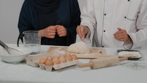 إعداد المخبوزات والمعجنات الشهية، المشاركة في تحضير الوصفات الشهية، الاستمتاع بالعمل الجماعي في مهنة الطبخ، تصوير مقرب ليد رجل وامرأة عربيين خليجيين اماراتيان يتشاركان في تجهيز الطعام، شيف خليجي يرتدي الزي الخاص بمزاولة المهنة مع القبعه البيضاء يحمل بيده الشوبك