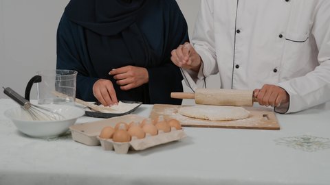 الاستمتاع بالعمل الجماعي في مهنة الطبخ، المشاركة في تحضير الوصفات الشهية، تصوير مقرب ليد رجل وامرأة عربيين خليجيين اماراتيان يقفان خلف الطاولة الخشبية ويتشاركان في تجهيز الطعام، إعداد المخبوزات والمعجنات الشهية