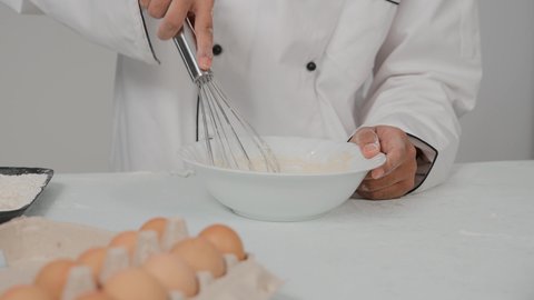 A group of easy and quick pastries with various foods, fresh popular baked goods, preparing delicious baked goods and pies, a close-up of the hand of an Emirati Gulf Arab chef wearing the uniform of the profession, holding a hand mixer in his hand, preparing the dough