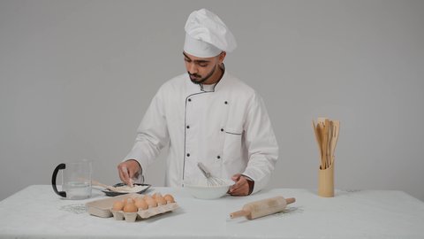 مخبوزات شعبية طازجة، تحضير المخبوزات والفطائر الشهية، مجموعة من المعجنات السهلة والسريعة بأطعمة متنوعة، تصوير مقرب  لشيف عربي خليجي اماراتي يرتدي الزي الخاص بمزاولة المهنة مع القبعه البضاء يقوم برش الدقيق على العجينه