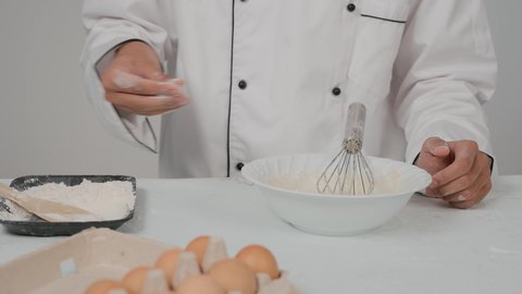 تحضير المخبوزات والفطائر الشهية، مجموعة من المعجنات السهلة والسريعة بأطعمة متنوعة، تصوير مقرب ليد شيف عربي خليجي اماراتي يرتدي الزي الخاص بمزاولة المهنة يقوم برش الدقيق على العجينه، مخبوزات شعبية طازجة