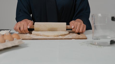 مسؤولية ربة المنزل، استخدام أداة فرد العجين، تصوير مقرب لامرأة عربية خليجية اماراتية محجبة ترتدي العباءه السوداء تحمل بيدها الشوبك (النشابة) تقوم بتحضير الطعام، تجهيز المكونات لصناعة الخبز، أدوات خاصة بالمطبخ، إعداد المخبوزات والمعجنات الشهية