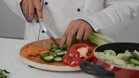 احتراف مهنة الشيف الطباخ، مهارات تقديم وتزيين الطعام بطرق مميزة ومبتكرة، المتعة في تحضير الوصفات الشهية, تصوير مقرب ليد شاب عربي خليجي اماراتي يرتدي زي الطهاة الخاص  ويقوم بإعداد بتقطيع الخس