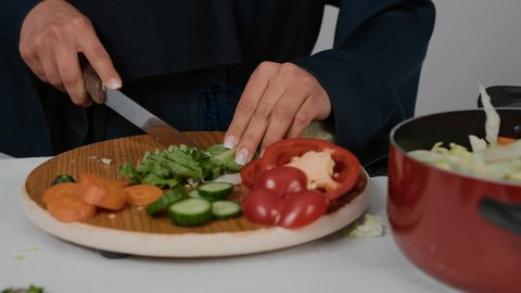 فنون ومهارات الطبخ، تحضير وتجهيز مكونات السلطات والاطباق الصحية ، تصوير مقرب لامراة عربية خليجية اماراتية ترتدي العباءة الكحلي تقوم بتقطيع الخس، سيده سعودية تقوم بقضاء أوقات ممتعه في المطبخ