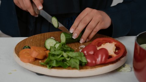 الوقوف أمام طاولة المطبخ، تحضير وتجهيز مكونات السلطات والاطباق الصحية، تعلم وتطبيق فنون الطهي ،تصوير مقرب لامراة عربية خليجية اماراتية ترتدي العباءة الكحلي تقوم بتقطيع الخيار، سيده سعودية تقوم بقضاء أوقات ممتعه في المطبخ