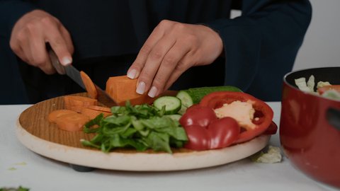 تحضير وتجهيز مكونات السلطات والاطباق الصحية، تعلم وتطبيق فنون الطهي ،تصوير مقرب لامراة عربية خليجية اماراتية ترتدي العباءة الكحلي تقوم يتقطيع الجزر، سيده سعودية تقوم بقضاء أوقات ممتعه في المطبخ