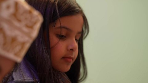 تصوير مقرب لطفله عربية عمانيه ترتدي جاكيت تنظر الي الاسفل، أداء الكثير من الأنشطة الممتعة، الاهتمام بالانشطه في رياض الأطفال والحاضنات، تنميه عقل الاطفال الصغار