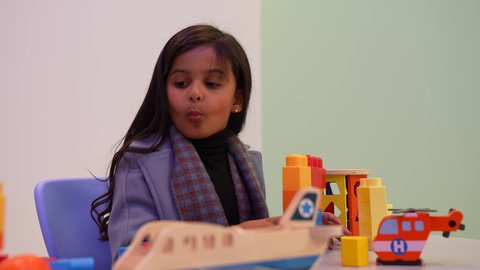 انشطة ترفيهية ابداعية، طفلة عربية خليجية سعودية تستمتع بتركيب المكعبات، الجلوس داخل غرفه الانشطه، ايماءات وجه تدل على السعادة، الابداع وتنمية المهارات، قضاء اوقات ممتعة، بنت  عمانيه داخل المدرسه