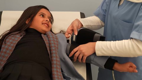 مفهوم الطب والرعاية الصحية، الفحص الطبي للأطفال، الرعاية الطبية للأطفال، طبيبه أطفال عربيه خليجيه سعوديه مع طفله صغيره تقوم بقياس الضغط،  ادوات القياس الطبيه الحديثه، بنت عربيه عمانيه مبتسمه تجري فحوصات طبيه