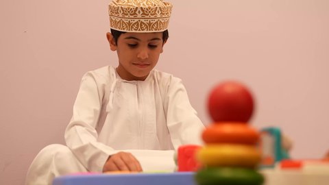 الجلسات والحصص الإبداعية في الروضات العمانيه، إيماءات وجه تدل على السعادة والمتعة والتركيز، اطفال يستمتعون بالعاب الذكاء في المدرسه، طفل عربي خليجى عماني يرتدي الدشداشه والكمه برفقه صديقته، اللعب سويا في المدرسه، لعبه برج هانوي