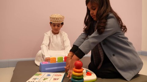 اللعب سويا في المدرسه، مهارات وأنشطة تساعد على التطور الفكري، الجلسات والحصص الإبداعية في الروضات العمانيه، إيماءات وجه تدل على السعادة والمتعة والتركيز، اطفال عرب عمانيون يستمتعون بالعاب الذكاء في المدرسه، طفل عربي خليجى عماني برفقه صديقته