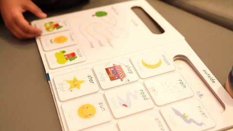 التعلم عن طريق الألعاب التثقيفية، الاهتمام بتعليم وترفيه الأبناء, التسلية والترفيه بالأنشطة التعليمية, التعرف على أشكال الحروف الأجنبية، تصويرمقرب ليد بنت سعوديه تقوم بقراءه كتيب الكلمات الانجليزيه برفقه صديقها، فتاه عمانيه تقوم بطي صفحات الكتاب