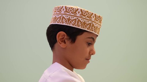 حضانة أطفال في سلطنه عمان، الاهتمام بالاطفال في الروضة، مشاركه اللعب بين الاطفال، تصوير مقرب لولد عماني يرتدي الدشداشه والكمه يقوم بالنظر الي شئ ما، ايماءه الفرح والسرور