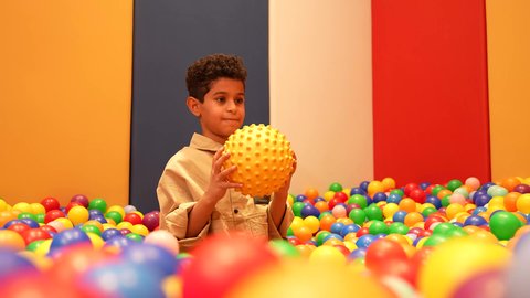 تعليم و ابداع و تنمية المهارات، حضانة أطفال في السعوديه، مشاركه اللعب بين الاطفال، الاهتمام بالاطفال في الروضة، ولد عماني يرتدي الزي الكاجوال تقوم باللعب في حوض الكور البلاستيكية الملونه، طفل سعودي يقوم بالتسلية والترفيه برفقه صديقه، ايماءه الفرح والسرور