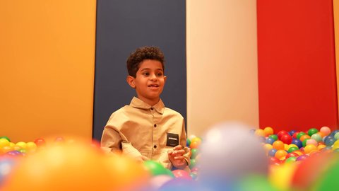 مشاركه اللعب بين الاطفال، الاهتمام بالاطفال في الروضة، ولد عماني يرتدي الزي الكاجوال تقوم باللعب في حوض الكور البلاستيكية الملونه، طفل سعودي يقوم بالتسلية والترفيه برفقه صديقه، ايماءه الفرح والسرور، تعليم و ابداع و تنمية المهارات، حضانة أطفال في السعوديه