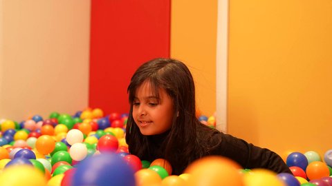 تعليم و ابداع و تنمية المهارات، بنت عمانيه ترتدي الزي الكاجوال تقوم باللعب في حوض الكور البلاستيكية الملونه، طفله سعوديه تقوم بالتسلية والترفيه، ايماءه الفرح والسرور، الاهتمام بالاطفال في الروضة