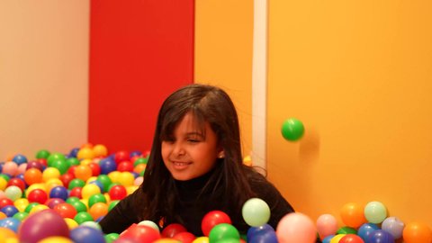 بنت عمانيه ترتدي الزي الكاجوال تقوم باللعب في حوض الكور البلاستيكية الملونه، طفله سعوديه تقوم بالتسلية والترفيه، ايماءه الفرح والسرور، تعليم و ابداع و تنمية المهارات، حضانة أطفال، الاهتمام بالاطفال في الروضة