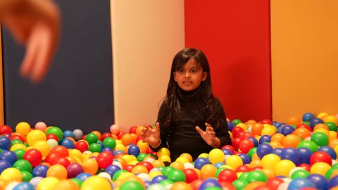 مشاركه اللعب بين الاطفال، بنت عمانيه ترتدي الزي الكاجوال تقوم باللعب في حوض الكور البلاستيكية الملونه، طفله سعوديه تقوم بالتسلية والترفيه برفقه صديقتها، ايماءه الفرح والسرور، تعليم و ابداع و تنمية المهارات، حضانة أطفال، الاهتمام بالاطفال في الروضة