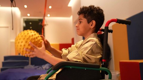 دعم ذوي الهمم والاهتمام بهم، ولد عربي عماني  يلعب بالكره، طفل سعودي يجلس علي كرسي متحرك في رياض الاطفال، اطفال ذوي الاحتياحات الخاصة والاهتمام بهم