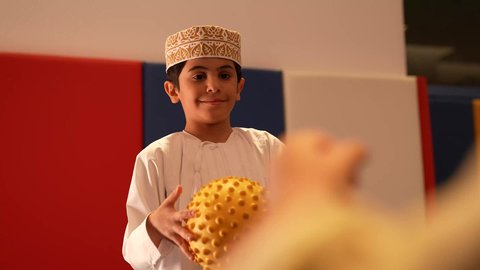 رياض الأطفال والحاضنات ، ولد عربي خليجي عماني مبتسم يرتدي الدشداشه والكمه يقوم باللعب بالكره برفقه صديقه، تعليم و ابداع و تنمية المهارات، الاهتمام بالاطفال في الروضة