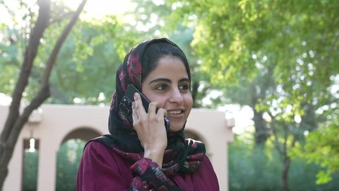 استخدام التقنيات الحديثة، الاستجمام بالطبيعة واستنشاق الهواء الطلق، تصوير لسيدة عربية خليجية عمانية ترتدي الزي العماني تسير فى احدي حدائق سلطنة عمان ،سيدة سعودية تخرج إلى أحد الاماكن العامة للترفيه عن النفس ، الاستمتاع بالأجواء في إحدى المنتزهات