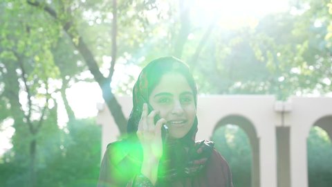 اجراء المكالمات الهاتفية، الاستجمام بالطبيعة واستنشاق الهواء الطلق، تصوير لسيدة عربية خليجية عمانية ترتدي الزي العماني تسير فى احدي حدائق سلطنة عمان ،سيدة سعودية تخرج إلى أحد الاماكن العامة للترفيه عن النفس ، الاستمتاع بالأجواء في إحدى المنتزهات