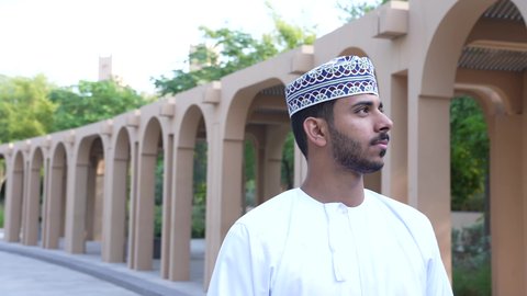 الاستجمام بالطبيعة واستنشاق الهواء الطلق، الاستمتاع بالأجواء في إحدى المنتزهات، رجل عربي خليجي عماني يرتدي الزي العماني يسير فى احدي حدائق سلطنة عمان ،الخروج إلى أحد الاماكن العامة للترفيه عن النفس