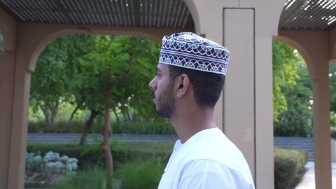 الاستجمام بالطبيعة واستنشاق الهواء الطلق، الخروج إلى أحد الاماكن العامة للترفيه عن النفس، الاستمتاع بالأجواء في إحدى المنتزهات، رجل عربي خليجي عماني يرتدي الزي العماني يسير فى احدي حدائق سلطنة عمان