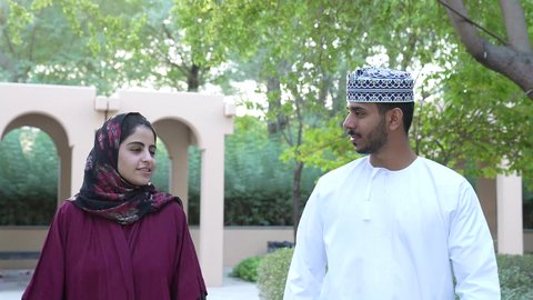 Taking a walk during the holiday time, participating in fun activities, a smiling Omani Gulf Arab couple walking together on a fun walk to one of the entertainment places, spending fun family times