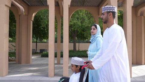 نزهة وجولة فى الهواء الطلق، تصوير لعائلة عربية خليجية عمانيه تجلس فى الحديقة ، ولد يجلس على كرسي متحرك  ، قضاء اوقات ممتعه مع العائله ،زوجان عربيان خليجيان عمانيان مستمتعان برفقه ابنهم