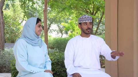 زوجان عربيان خليجيان عمانيان يقومان بإلتقاط صور سيلفي تذكارية بإستخدام الهاتف المحمول، أنشطة عائلية ترفيهية ، التنزه في حدائق سلطنه عمان, الجلوس في الهواء الطلق و الطبيعة الخضراء