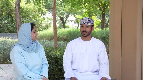 أنشطة عائلية ترفيهية ، التنزه في حدائق سلطنه عمان, الجلوس في الهواء الطلق و الطبيعة الخضراء, زوجان عربيان خليجيان عمانيان يقومان بإلتقاط صور سيلفي تذكارية بإستخدام الهاتف المحمول