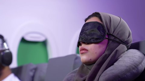 مفهوم النوم والراحه في الرحلة السياحية ، تصوير مقرب من الجانب لامرأة عربية عمانيه خليجية نائمه على كرسيها في الطائرة، الشعور بالتعب والارهاق والحاجة الى النوم والراحة، قضاء العطلة الصيفية في السفر والسياحه, خطوط الطيران العماني