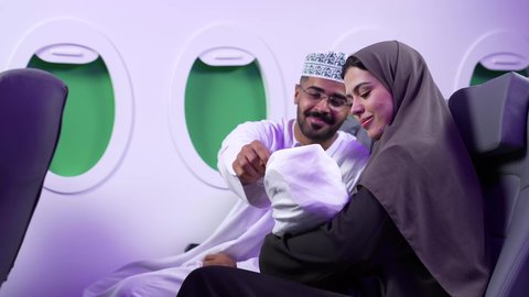 إيماءات وجه مختلفة تدل على الحب والأمان، تصوير مقرب من الجانب لرجل وامراه عربييان خليجييان عمانييان يرتديان الزى العماني يجلسان على كرسيان داخل الطائره ، اجواء عائليه دافئه ،  مفهوم الأمومة والطفولة ، الأسرة وتحمل المسؤولية
