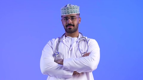 مفهوم الطب والرعاية الصحية ، العمل في القطاع الصحي لتقديم الخدمات الصحية ، تصوير لطبيب عربي خليجي عماني بإيدي متقاطعة ، ينظر إلى الكاميرا ، يقدم خدماته للمرضى بكل كفاءه ، مهن ووظائف طبية