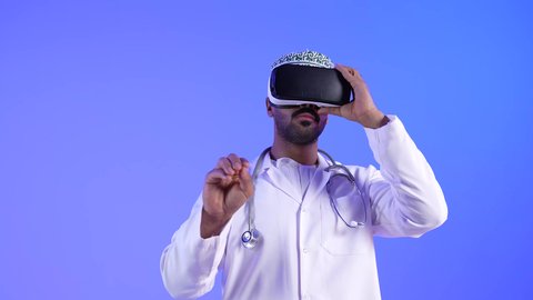 مفهوم التقنيات الإلكترونية الحديثة، حركة اصبع واشارات ، تصويرلطبيب خليجي عماني يرتدي نظارات الواقع الإفتراضي (في آر) ثلاثية الأبعاد ويقوم بإيماءات يد مختلفة، يشير بإصبعه السبابة، النقر والضغط، إستخدام حاسة اللمس