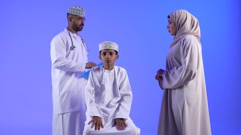 موعد مع الطبيب لتلقي العلاج ، الفحص الطبي للأطفال ، تقديم الرعاية والخدمات الصحية ، تصوير مقرب لطبيب خليجي عماني يرتدي الكمامه مع طفل ، مفهوم الطب والرعاية الصحية ، مهن ووظائف طبية ، تفحص الطبيب حالة المريض عبر سماعة الأذن ، تشخيص حالة المريض