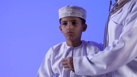 الفحص الطبي للأطفال ، تقديم الرعاية والخدمات الصحية ، تصوير لطبيبة خليجية عمانيه مع طفل ، مفهوم الطب والرعاية الصحية ، مهن ووظائف طبية ، تفحص الطبيبة حالة المريض عبر سماعة الأذن ، موعد مع الطبيب لتلقي العلاج ، تشخيص حالة المريض