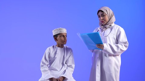 مراجعة الطبيب حالة الطفل ، موعد مع الطبيب لتلقي العلاج ، تفحص الطبيبة حالة المريض ،  تصوير لطبيبة خليجية عمانيه مع طفل ، مفهوم الطب والرعاية الصحية ، الفحص الطبي للأطفال ، تقديم الرعاية والخدمات الصحية ، مهن ووظائف طبية ، تشخيص حالة المريض