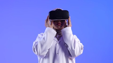 إستخدام التقنيات الإلكترونية الحديثة ، مفهوم الطب والرعاية الصحية ، تصوير لطبيبة عربية خليجية سعودية ترتدي نظارات الواقع الإفتراضي (في آر) ثلاثية الأبعاد ، مهن ووظائف طبية ، النظر من خلال نظارات الواقع الإفتراضي بإيماءات وجه ويدين مختلفة