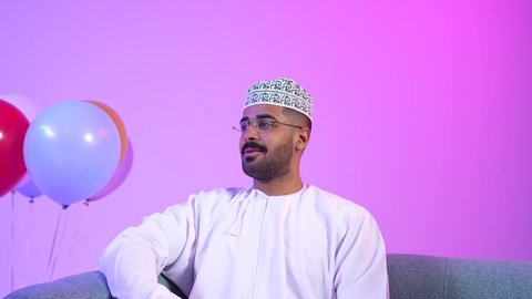 Offering Arabic hospitality and traditional sweets, exchanging greetings, the Omani family gathering to welcome the blessed Eid, the concept of tenderness, love and affection, showing feelings of joy and happiness at the arrival of Eid, offering Saudi dates, a picture of an Arab Gulf Omani family sitting in the living room with gestures of happiness