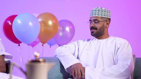 مفهوم الحنان والمحبة والمودة، إظهار مشاعر الفرح والسعادة بقدوم العيد، تقديم التمر السعودي ، تجمع العائلة العمانية لاستقبال العيد المبارك, تقديم الضيافة العربية والحلويات الشعبية، تبادل المعايدات, تصوير لعائلة عربية خليجية عمانية تجلس في غرفة المعيشة بايماءات السعادة