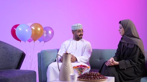 تجمع العائلة العمانية لاستقبال العيد المبارك, تقديم الضيافة العربية والحلويات الشعبية، الزينة والبلالين والاحتفالات، تبادل المعايدات, مفهوم الحنان والمحبة والمودة، إظهار مشاعر الفرح والسعادة بقدوم العيد، تصوير لعائلة عربية خليجية عمانية تجلس في غرفة المعيشة بايماءات السعادة
