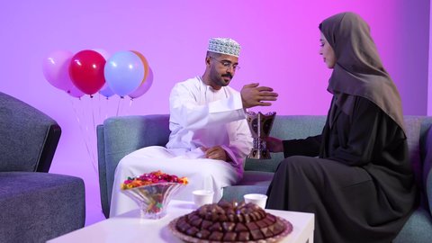 تبادل المعايدات, مفهوم الحنان والمحبة والمودة، إظهار مشاعر الفرح والسعادة بقدوم العيد، تقديم الضيافة العربية والحلويات الشعبية، تجمع العائلة العمانية لاستقبال العيد المبارك, الزينة والبلالين والاحتفالات، تصوير لعائلة عربية خليجية عمانية تجلس في غرفة المعيشة بايماءات السعادة