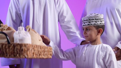تجمع العائلة العمانية لاستقبال العيد المبارك,  تبادل المعايدات, تقديم الضيافة العربية والحلويات الشعبية، مفهوم الحنان والمحبة والمودة، إظهار مشاعر الفرح والسعادة بقدوم العيد، تقديم التمر السعودي ، تصوير لعائلة عربية خليجية عمانية تجلس في غرفة المعيشة بايماءات السعادة