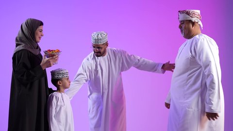 إظهار مشاعر الفرح والسعادة، طقوس الاحتفالات والمناسبات السعيدة في سلطنة عمان، تبادل المعايدات في الأعياد، عائلة عربية خليجية عمانية تحتفل بالعيد المبارك، خلفية ملونة